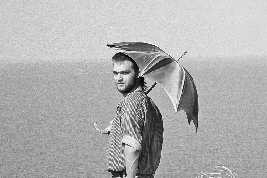 Mann mit Regenschirm an Küste