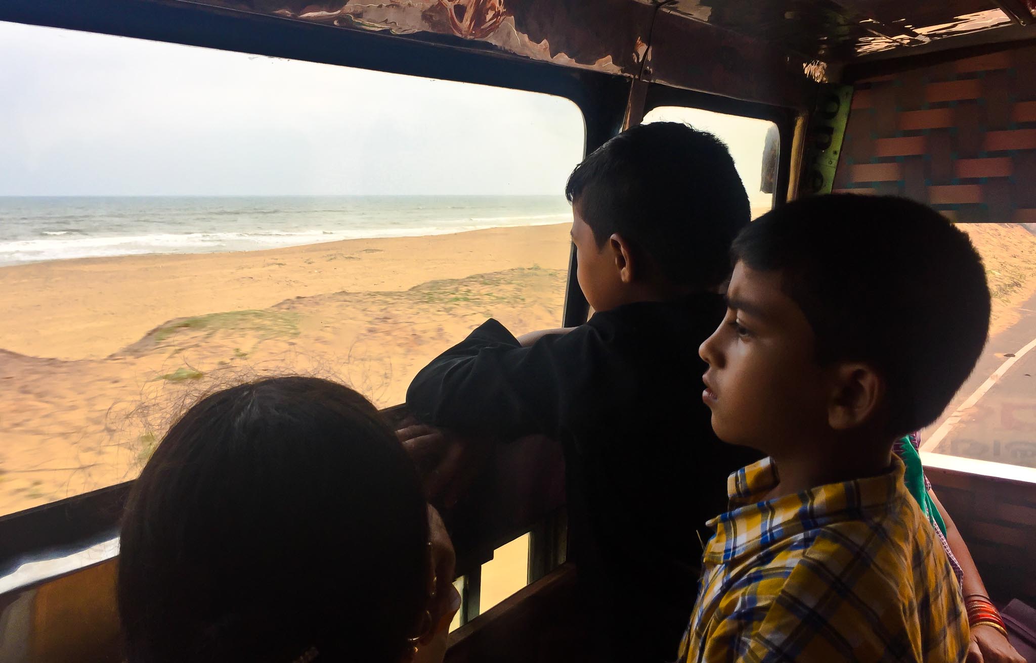 Boys watching the beach from school bus, Konark, Odisha, India
